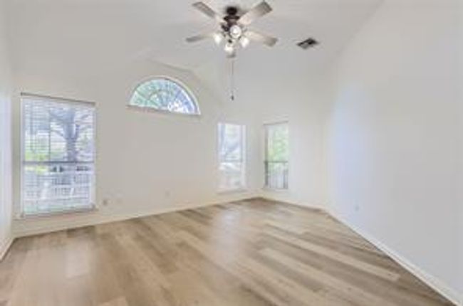 Spare room featuring ceiling fan, wood finished floors, and high vaulted ceiling | Image 12