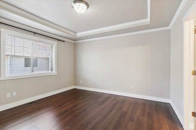 Unfurnished room featuring a tray ceiling, dark wood-type flooring, baseboards, and crown molding | Image 16