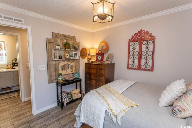 Bedroom featuring visible vents, baseboards, an inviting chandelier, wood finish floors, and ornamental molding | Image 25