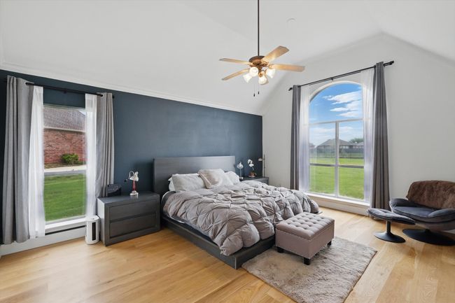 Elegant solid hardwood flooring extends through a spacious master bedroom overlooking private backyard with dramatic accent wall. | Image 17
