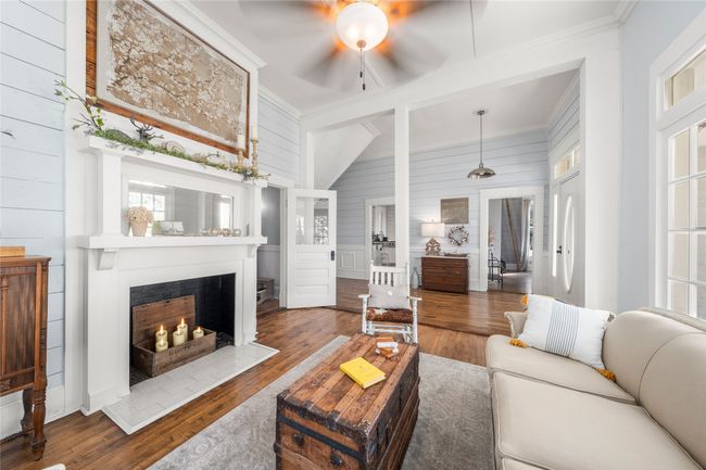 Living room featuring ceiling fan, hardwood / wood-style flooring, healthy amount of natural light, crown molding, and wooden walls, fireplace | Image 15