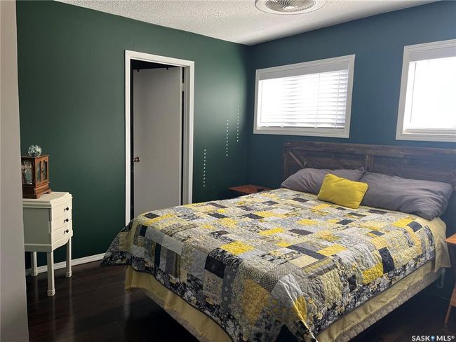 Bedroom featuring a textured ceiling, dark wood-style flooring, and multiple windows | Image 29