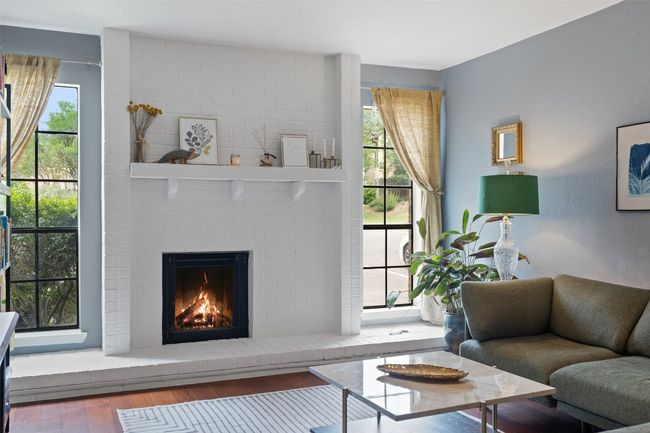 Living area with plenty of natural light, wood finished floors, and a fireplace | Image 15