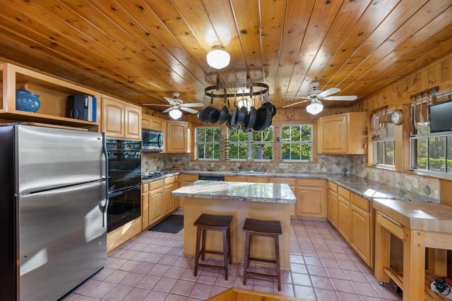 The kitchen is a culinary enthusiast's delight, complete with a suite of premium features. This includes a 5-burner gas stove, a convenient double oven setup, a built-in 36” microwave, pantry, and granite countertops that exude both style and practicality. The generously sized island serves as a focal point, providing ample space for food preparation and casual dining. | Image 14