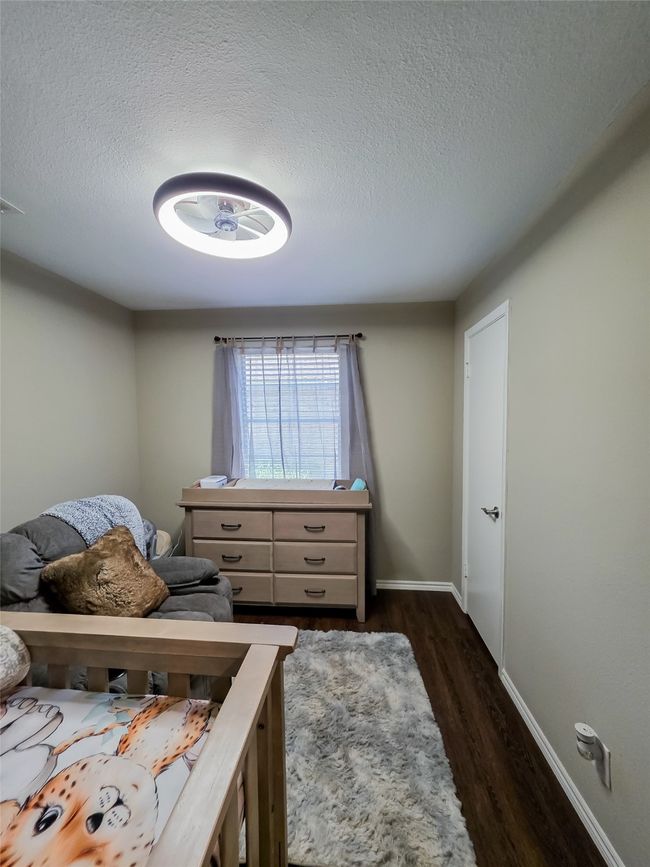 Bedroom with dark wood finished floors, a textured ceiling, and baseboards | Image 10