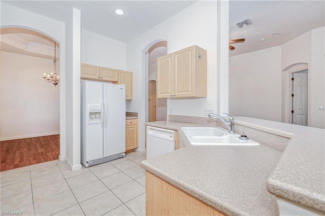 Kitchen with white appliances, light brown cabinetry, sink, and light tile patterned floors | Image 28