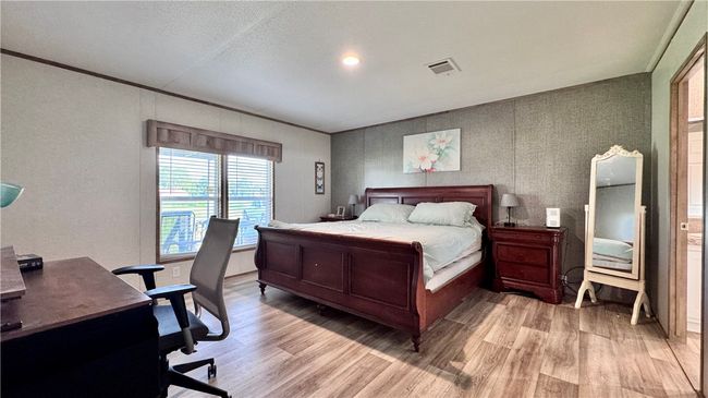 Bedroom featuring light wood-style floors, a desk, ornamental molding, and a textured ceiling | Image 18