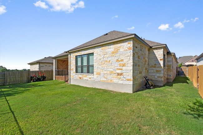 Back of house with stone siding, a fenced backyard, and a shingled roof | Image 31