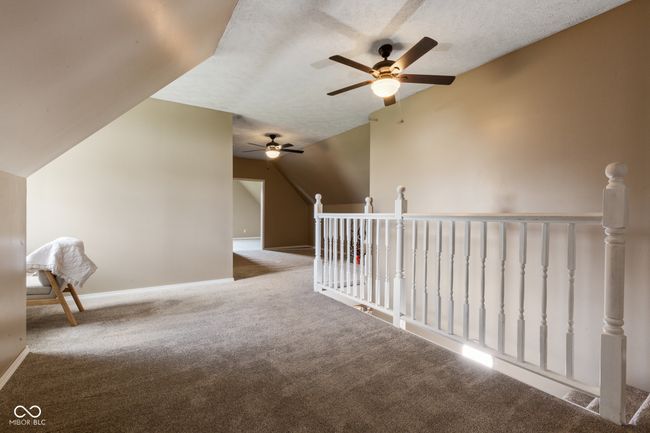 interior space with a textured ceiling, vaulted ceiling, carpet floors, an upstairs landing, and baseboards | Image 24