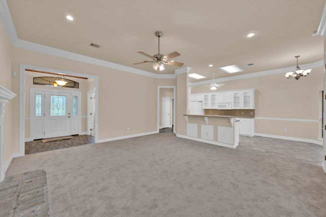 Unfurnished living room featuring carpet floors, ceiling fan, ornamental molding, a chandelier, and recessed lighting | Image 7