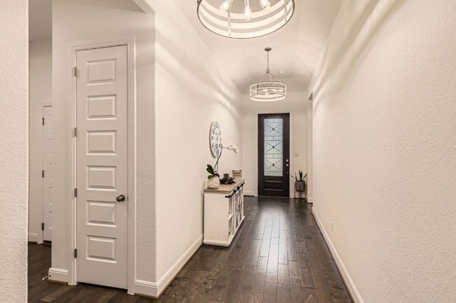 Entrance foyer with a chandelier, dark wood finished floors, and a textured wall | Image 4