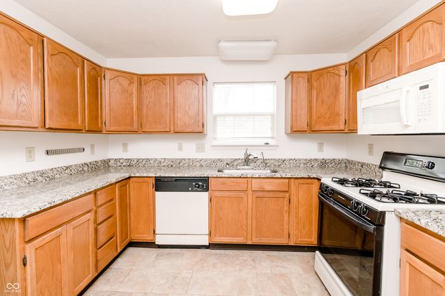 kitchen with light stone countertops, a sink, and white appliances | Image 10
