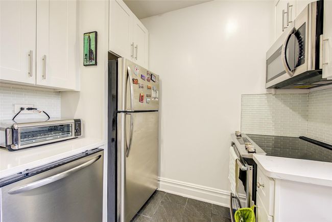 Kitchen featuring a toaster, white cabinetry, light stone counters, and appliances with stainless steel finishes | Image 6