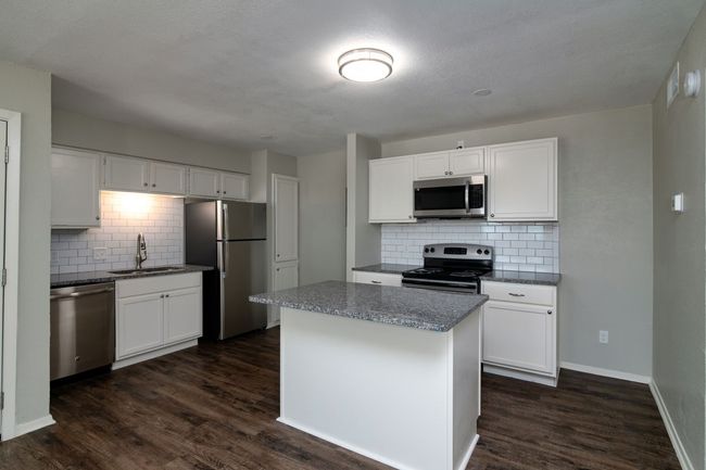 Kitchen with dark wood finished floors, backsplash, appliances with stainless steel finishes, and a sink | Image 4
