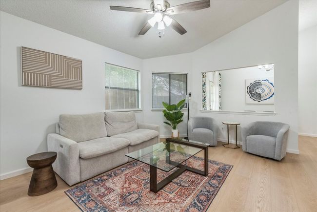 Living room with ceiling fan, baseboards, vaulted ceiling, and wood finished floors | Image 5