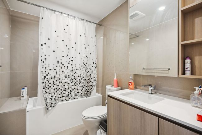 Bathroom with tile walls, visible vents, toilet, vanity, and shower / bath combo with shower curtain | Image 16
