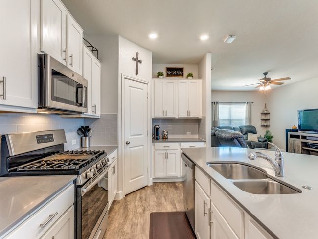 Kitchen featuring appliances with stainless steel finishes, light wood-style floors, open floor plan, white cabinetry, and a ceiling fan | Image 13