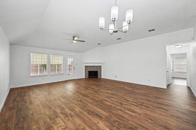 Unfurnished living room with a ceiling fan, lofted ceiling, dark wood finished floors, a chandelier, and a fireplace | Image 17