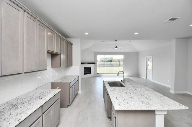 Culinary haven, featuring granite countertops, a tile backsplash, stainless steel appliances (to be installed), and 42” upper cabinets. | Image 14