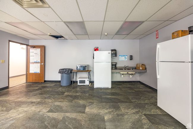 Kitchen featuring freestanding refrigerator, a drop ceiling, and stone finish floors | Image 23