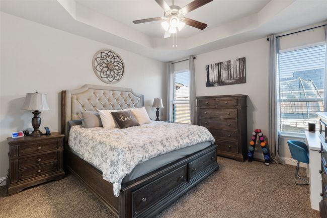 Bedroom with carpet, baseboards, a tray ceiling, and a ceiling fan | Image 22