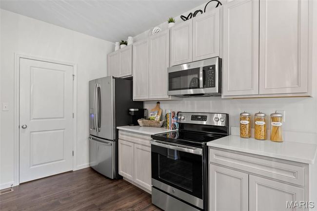 Kitchen with appliances with stainless steel finishes, light countertops, dark wood-type flooring, and white cabinets | Image 17