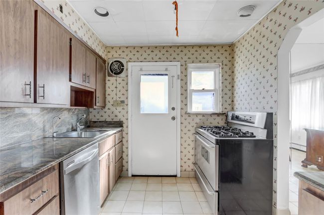 Kitchen featuring wallpapered walls, visible vents, appliances with stainless steel finishes, and a sink | Image 9