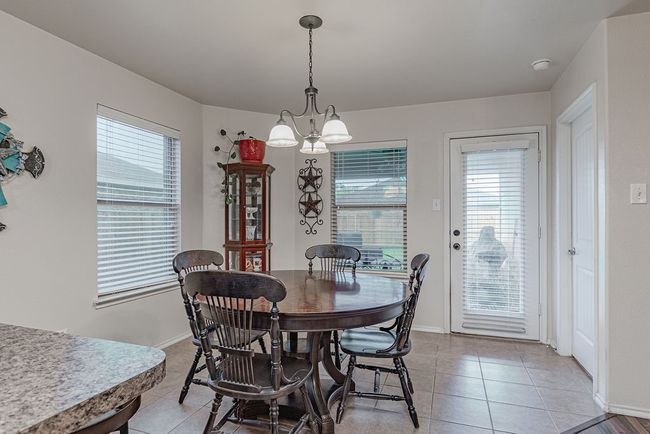 Dining area featuring light tile patterned flooring, baseboards, and a chandelier | Image 10
