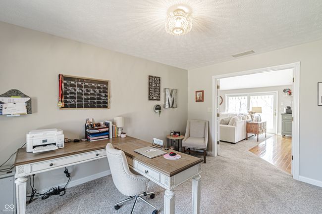 carpeted home office featuring baseboards, a textured ceiling, and visible vents | Image 15