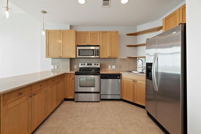 A closer view of the kitchen with its granite and stainless. The long breakfast bar can serve as your dining space. | Image 6