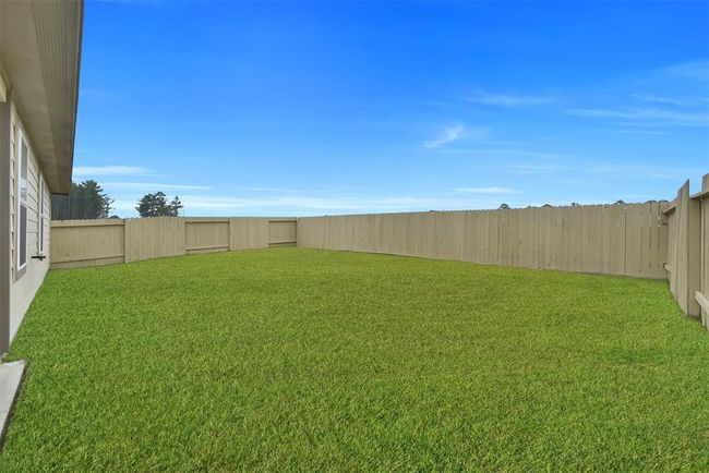 A spacious, fenced backyard with well-maintained grass, ideal for outdoor activities and privacy. | Image 23