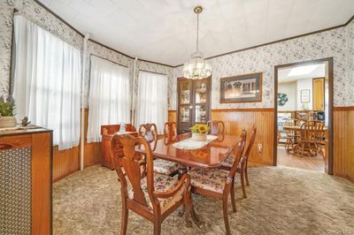 Dining area featuring an inviting chandelier, ornamental molding, light hardwood / wood-style floors, and wood walls | Image 2