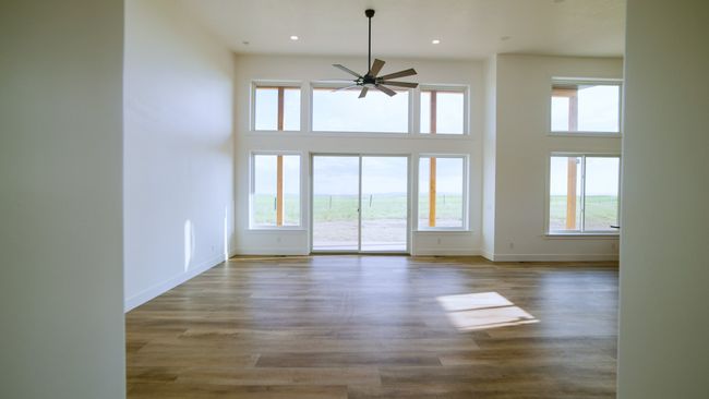 Unfurnished living room with healthy amount of natural light, a ceiling fan, a high ceiling, recessed lighting, and wood finished floors | Image 23