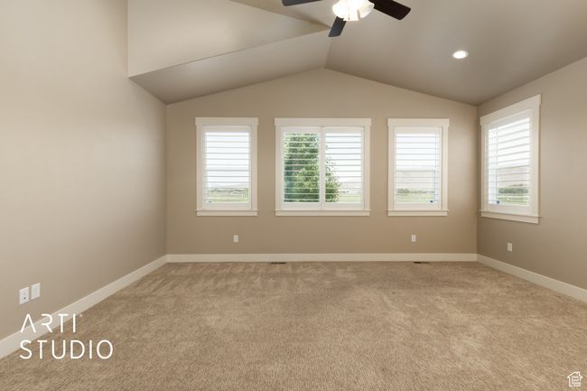 Empty room with a ceiling fan, light carpet, and lofted ceiling | Image 23