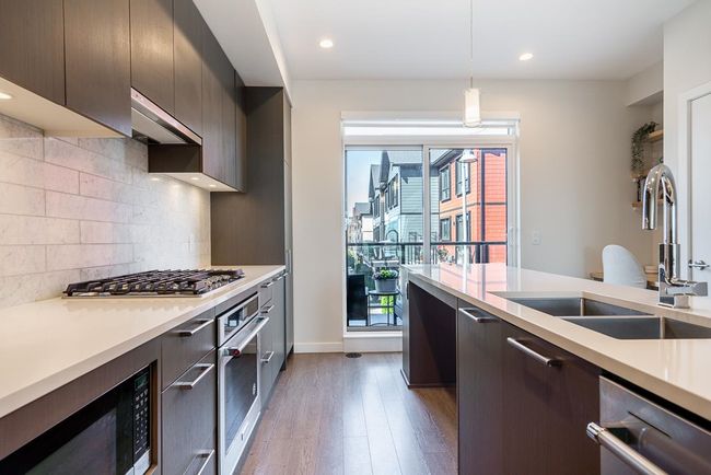 Kitchen featuring a sink, appliances with stainless steel finishes, under cabinet range hood, and light countertops | Image 4