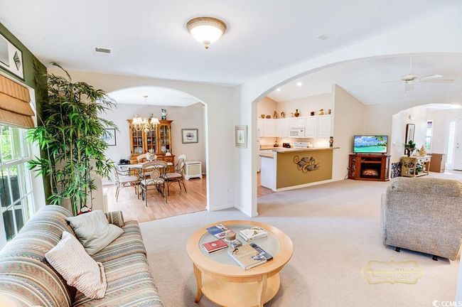 Living room featuring arched walkways, vaulted ceiling, a chandelier, a ceiling fan, and light colored carpet | Image 11