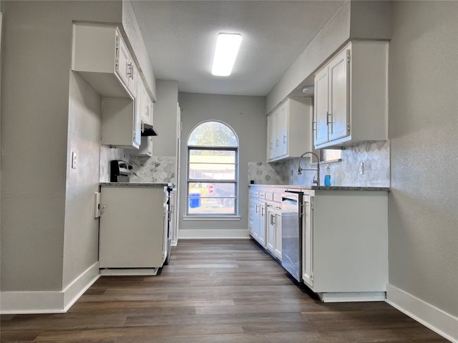 Kitchen with tasteful backsplash, dark hardwood / wood-style floors, stainless steel dishwasher, sink, and white cabinets | Image 7