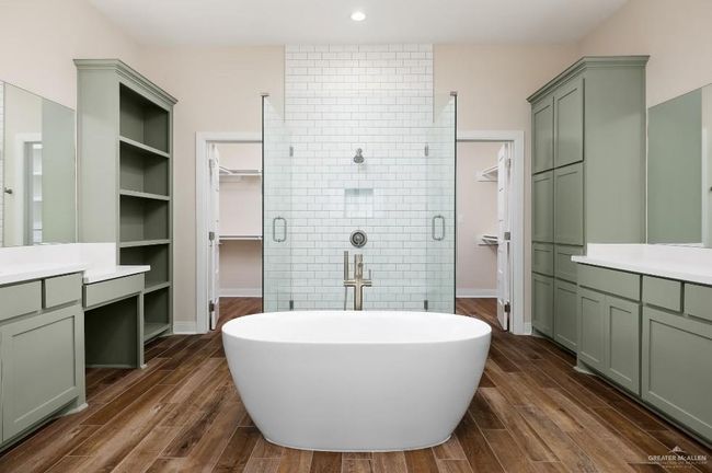 Full bath with a freestanding tub, vanity, wood finished floors, a walk in closet, and a stall shower | Image 19
