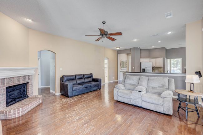 Living area with arched walkways, ceiling fan, light wood-style flooring, a fireplace, and recessed lighting | Image 6