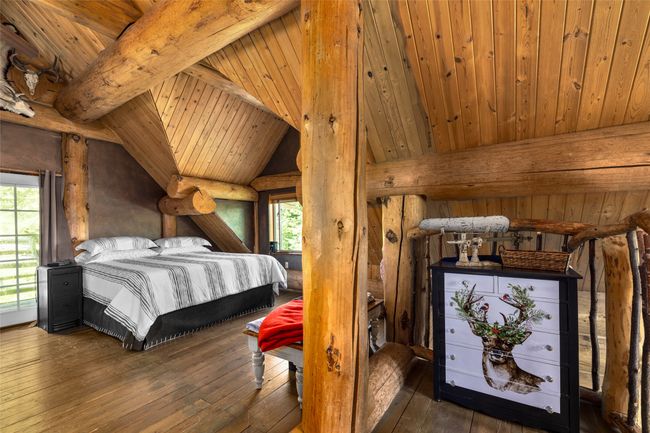 Bedroom featuring hardwood / wood-style floors, wooden ceiling, and log walls | Image 19