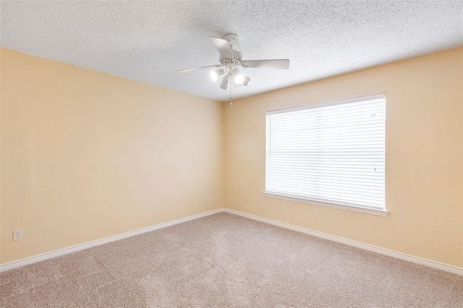 Empty room with carpet, a textured ceiling, baseboards, and ceiling fan | Image 14