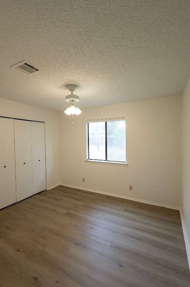 Unfurnished bedroom featuring wood finished floors, a textured ceiling, baseboards, and a closet | Image 21