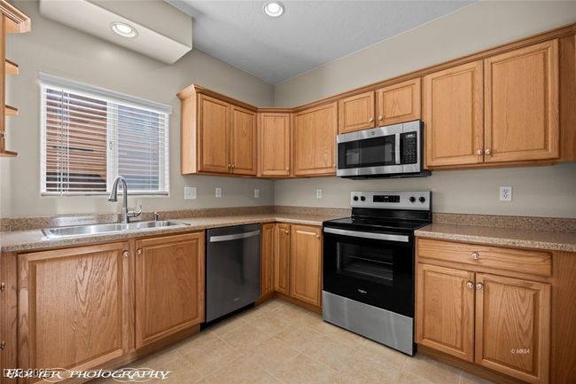 Kitchen featuring light countertops, a sink, appliances with stainless steel finishes, and recessed lighting | Image 11