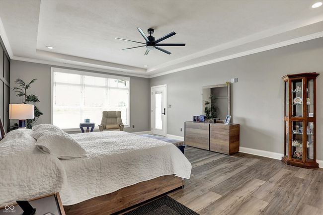 bedroom with baseboards, a tray ceiling, and light wood-style floors | Image 26