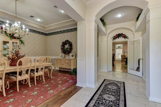Dining room with arched walkways, visible vents, a chandelier, ornate columns, and crown molding | Image 6