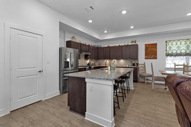 The heart of the home! A gourmet kitchen featuring an oversized granite island, custom designer vent hood, sleek appliances, and an enormous walk-in pantry. Style meets function in this entertainer’s dream. | Image 10
