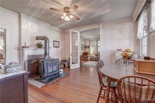 Dining space with a wood stove, french doors, ornamental molding, a ceiling fan, and wood finished floors | Image 15