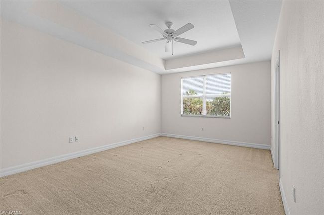Spare room featuring light colored carpet, ceiling fan, and a tray ceiling | Image 21