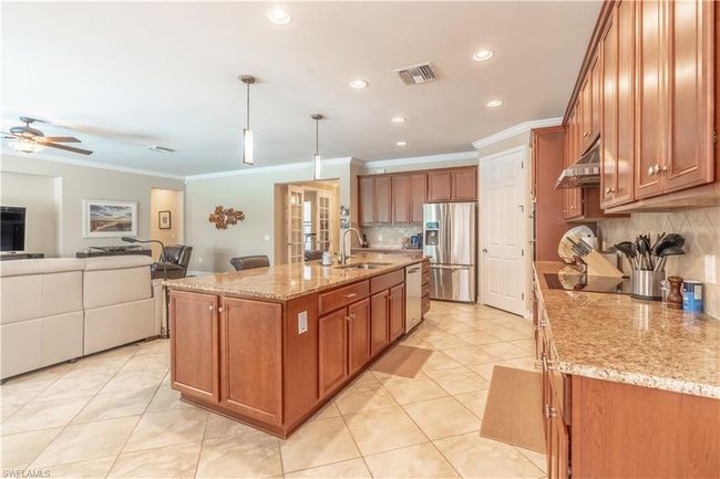 Dining room with light tile patterned floors, ceiling fan with notable chandelier, crown molding, and sink | Image 14