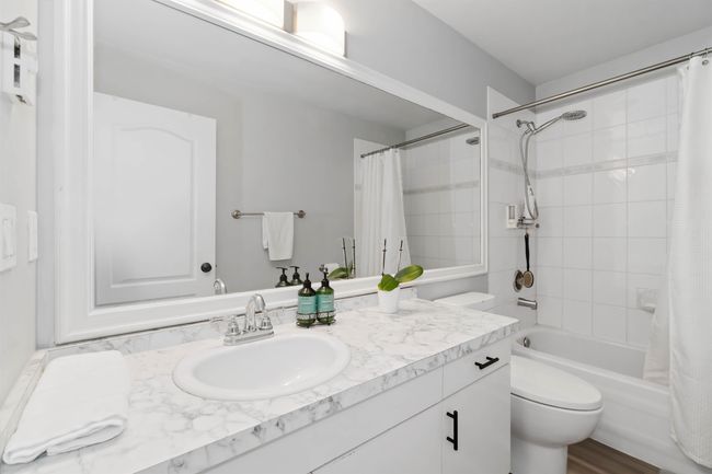 Bathroom with toilet, vanity, and shower / bath combination with curtain | Image 15